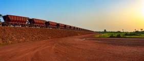 Railway carriages for transportation of bauxite ore on train tracks at the end of the railway line from bauxite mining. Guinea, Africa.